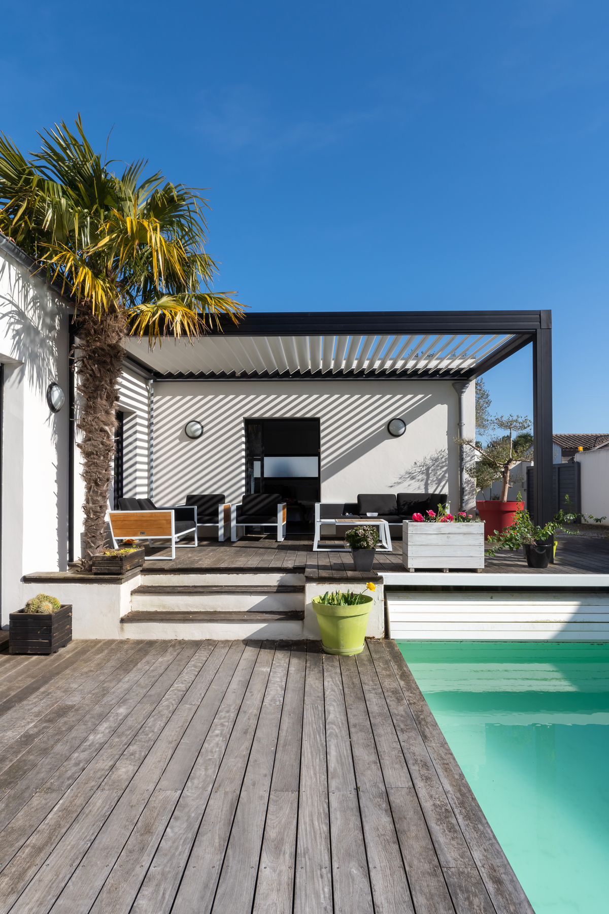 pergola stíní moderní terasu s bazénem