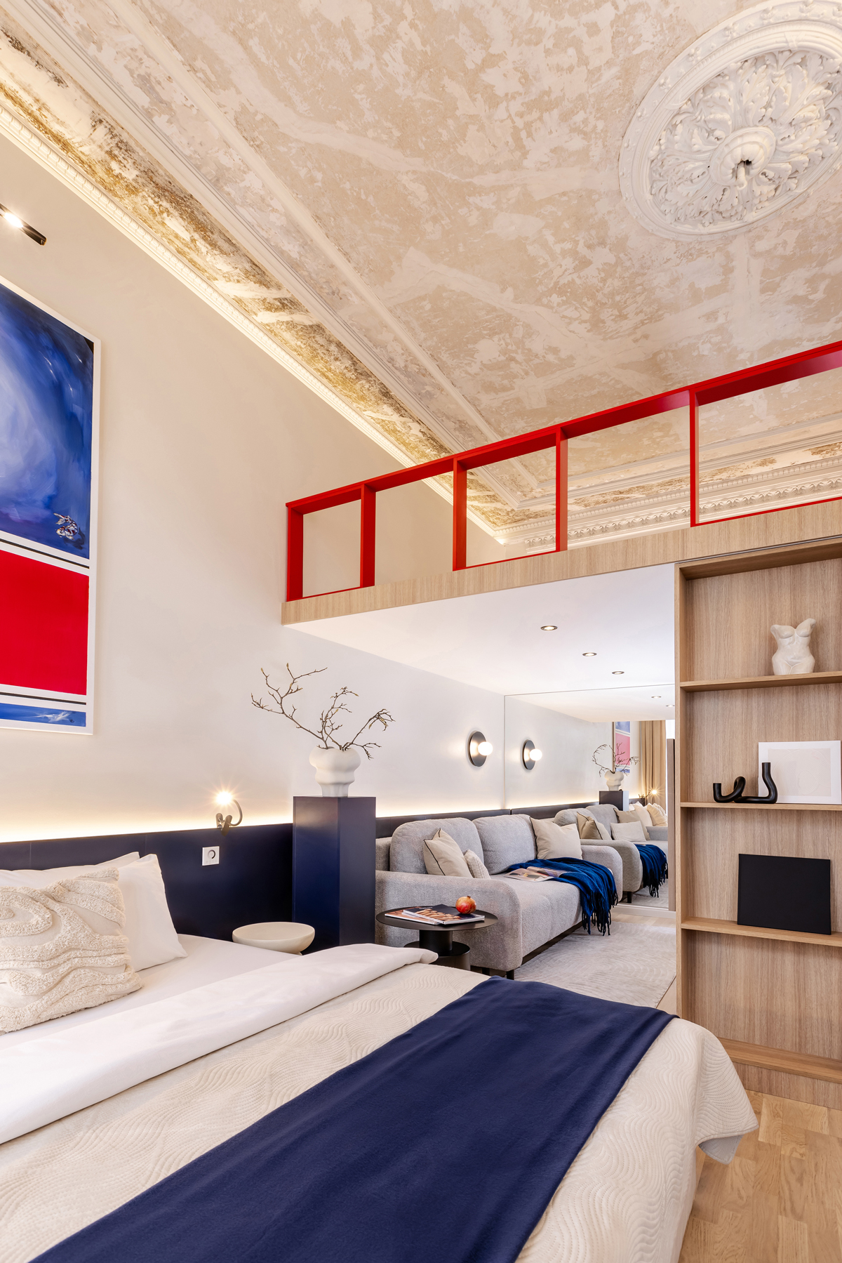 Detailní pohled z ložnice směrem k obývací části s pohovkou a designovým stropem.
