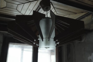 Detail černého vintage lustru s futuristickým vzhledem a matným sklem ve starém interiéru.