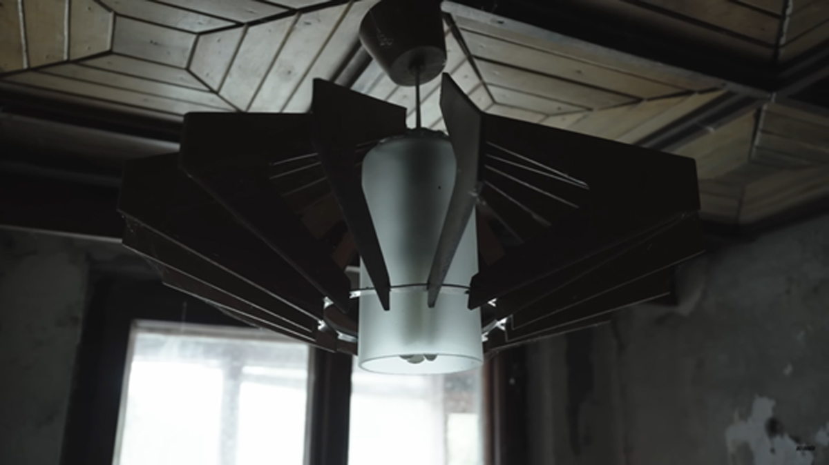 Detail černého vintage lustru s futuristickým vzhledem a matným sklem ve starém interiéru.