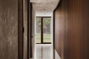 Minimalistická chodba v moderním domě s dřevěnými detaily a betonovou stěrkou