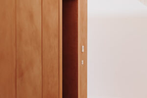 Detail minimalistické vestavěné skříně s hladkým dřevěným povrchem v podkroví.