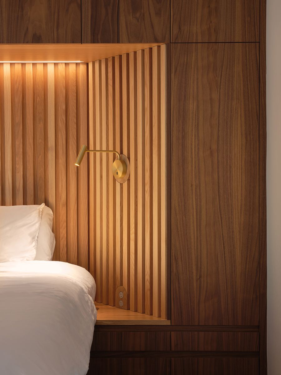 Luxusní ložnice s dřevěným obkladem, zabudovaným nočním světlem a moderním designem.