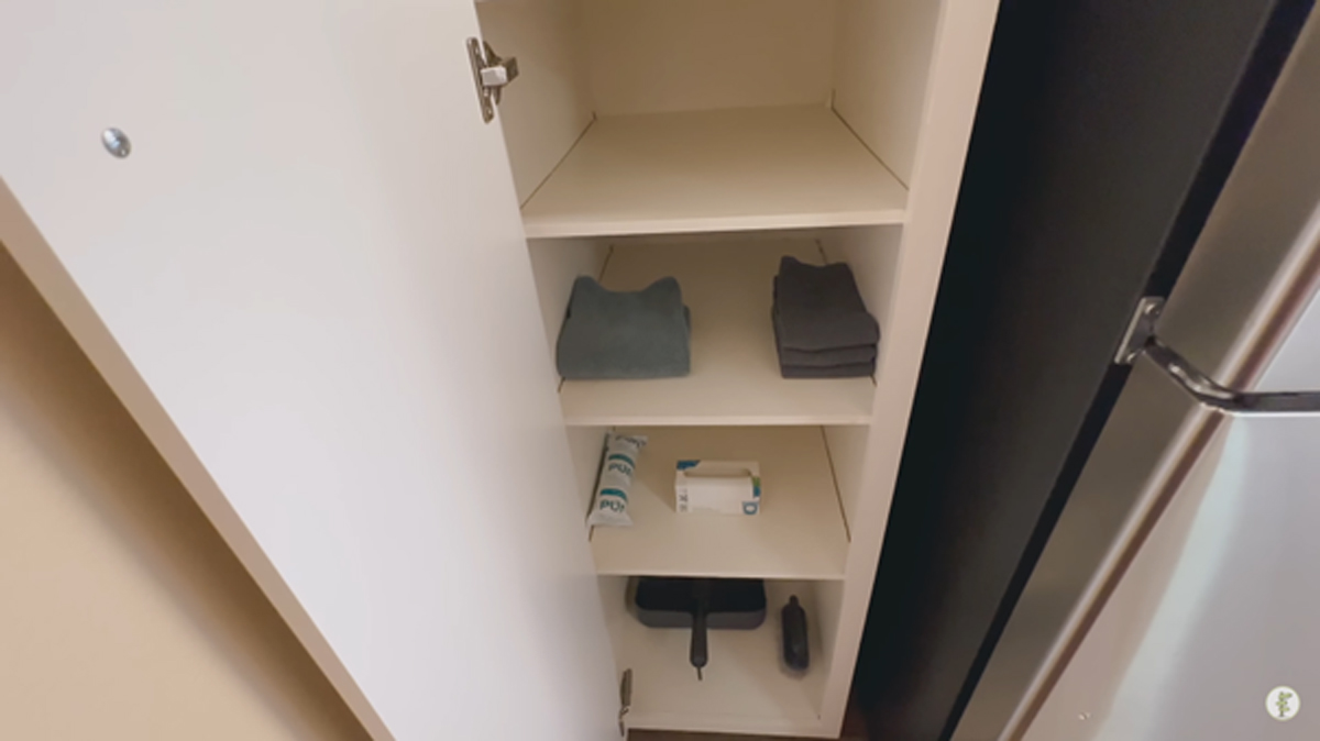 Otevřená skříň s několika ručníky, žínkami a úklidovými prostředky, ukázka minimalistického přístupu.