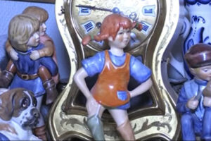 Porcelánové sošky dětských postaviček včetně Pipi Dlouhé punčochy před zlatými hodinami a dalšími figurkami.