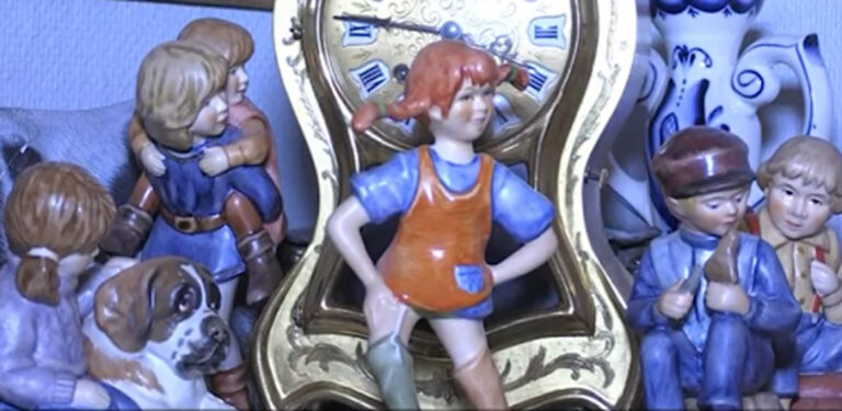 Porcelánové sošky dětských postaviček včetně Pipi Dlouhé punčochy před zlatými hodinami a dalšími figurkami.