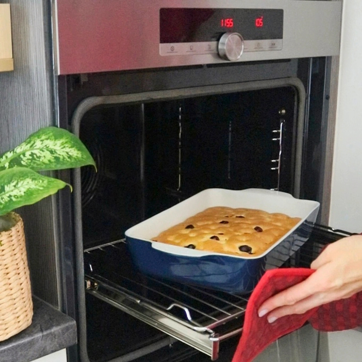 Vkládání pekáče s koláčem do rozehřáté trouby – zlatavé těsto s borůvkami.