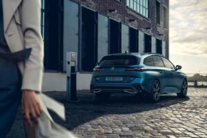 Peugeot 308 SW připojený k nabíjecí stanici na městské ulici.