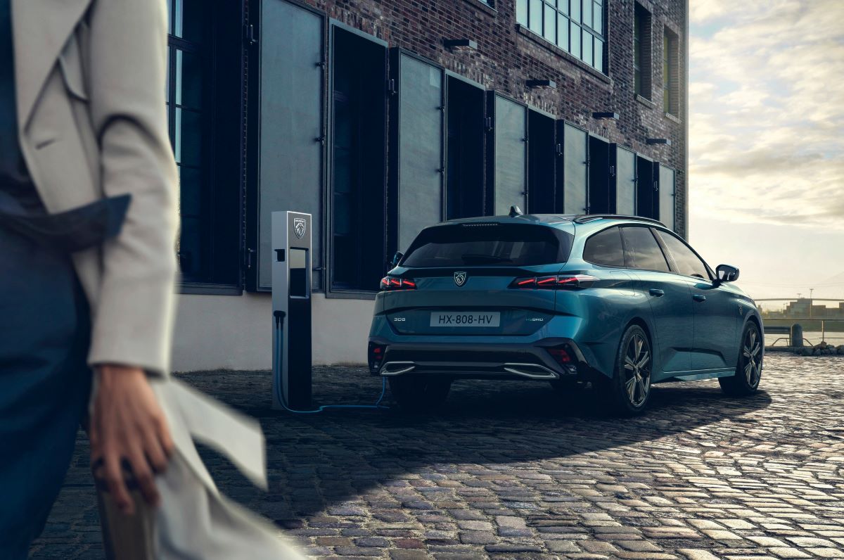 Peugeot 308 SW připojený k nabíjecí stanici na městské ulici.