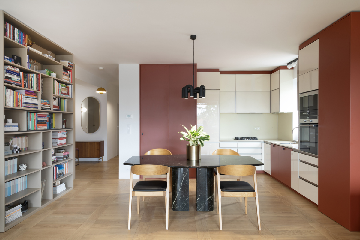 Černý mramorový stůl, dubové židle a kuchyně s krémovými dvířky a terakotovými panely; moderní elegance, hřejivá nálada.