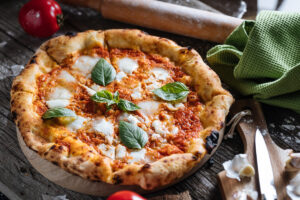 Čerstvě upečená pizza margherita s rajčatovou omáčkou, vláčnou mozzarellou a lístky bazalky; křupavý „leopardí“ okraj, sladkokyselá rajčata a jemně kouřová chuť.