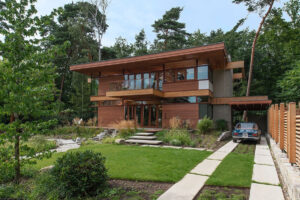 Moderní dům v Kleinmachnow kombinuje dřevěné obklady, betonové prvky a velká okna, což působí jako architektura inspirovaná americkými vilami.