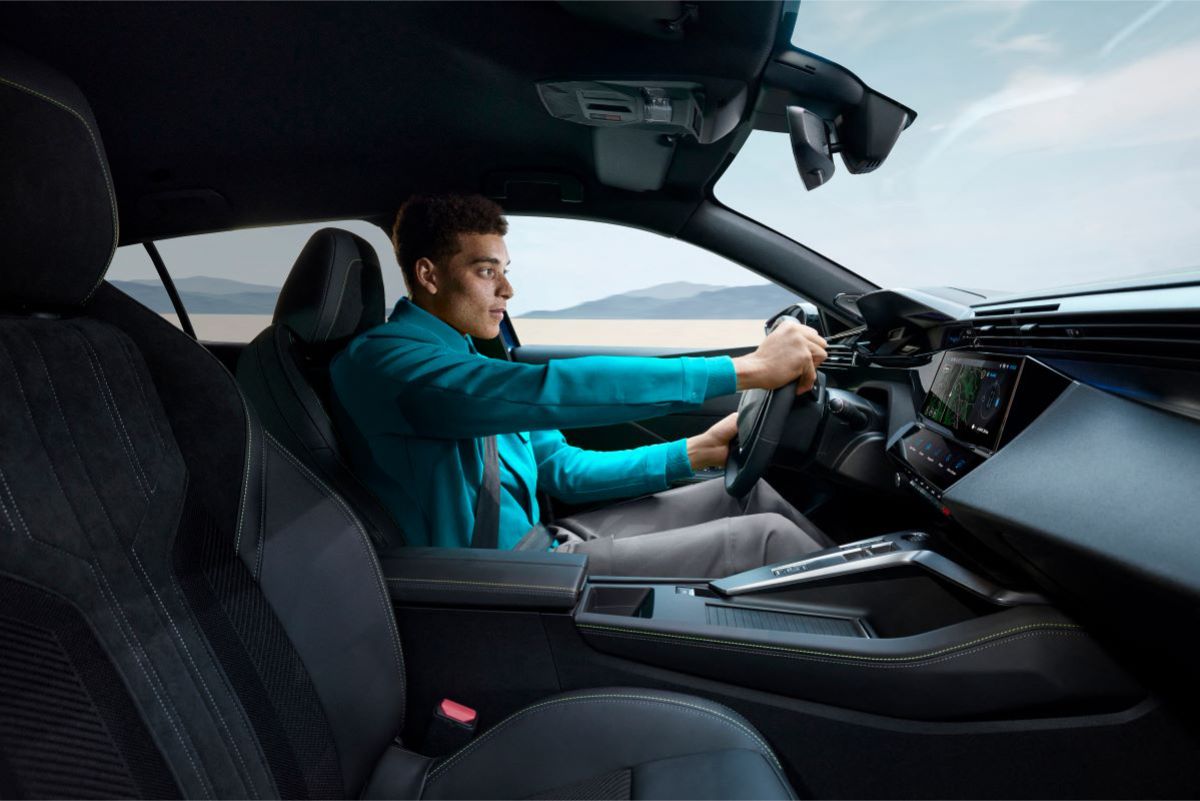 Muž za volantem vozu Peugeot 408, soustředěný na řízení s výhledem na moderní palubní desku.