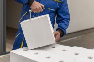 Detail stavební tvárnice Sendwix od KM BETA, kterou obsluhuje pracovník s natahovacím nástrojem.