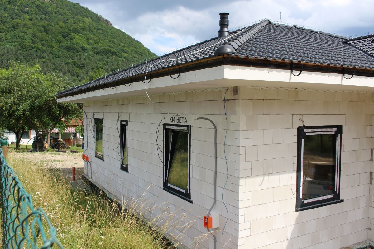 Dokončený rodinný dům postavený z bílých tvárnic KM BETA s černými okny a střechou.