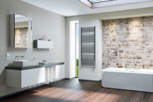 Koupelnový radiátor KORALUX LINEAR CLASSIC v antracitové barvě – elegantní topný žebřík do designové koupelny s cihlovou stěnou.