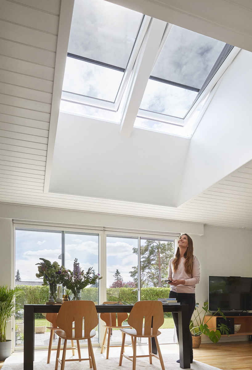 Jídelna s dvojicí střešních oken VELUX s venkovními markýzami, prosvětlený interiér s výhledem do zahrady