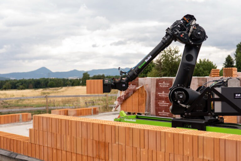 Detail zdicího robota při manipulaci s cihlou na stavbě.