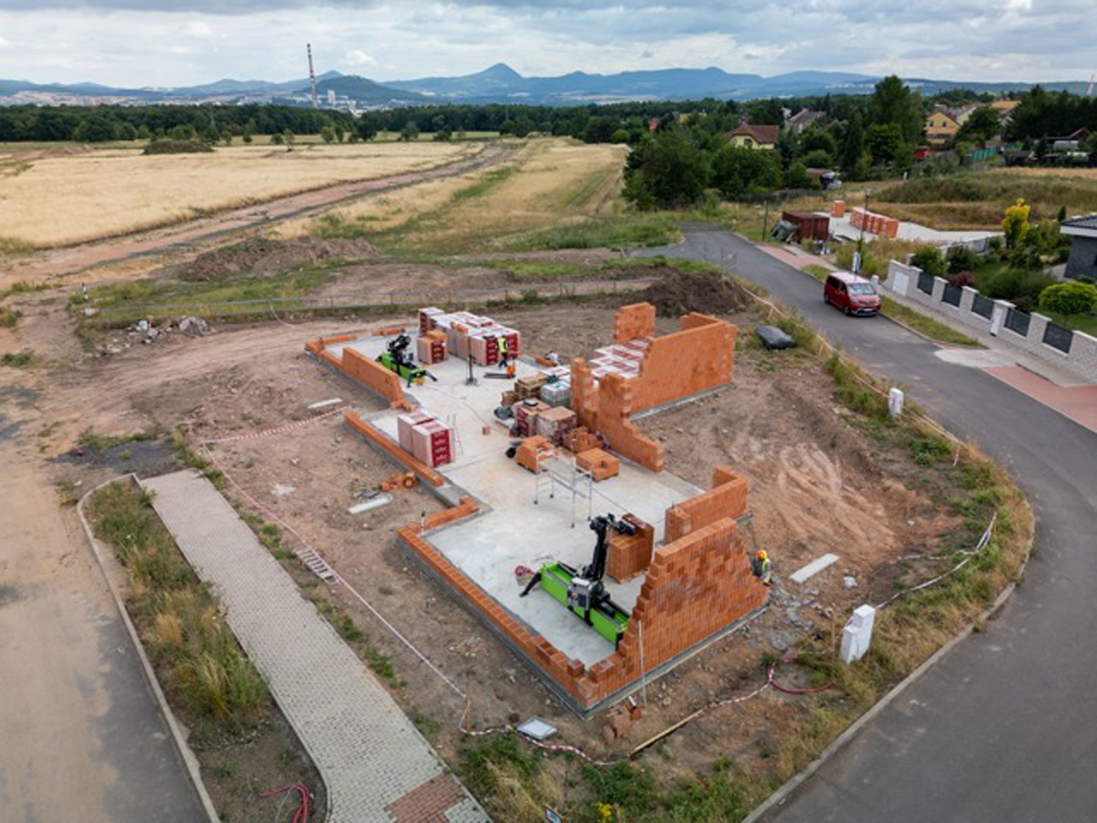 Stavba rodinného domu se zdicím robotem, který automaticky skládá cihly.