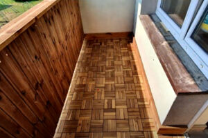 Zrekonstruovaný balkon s dřevěným obložením a moderní dlažbou.