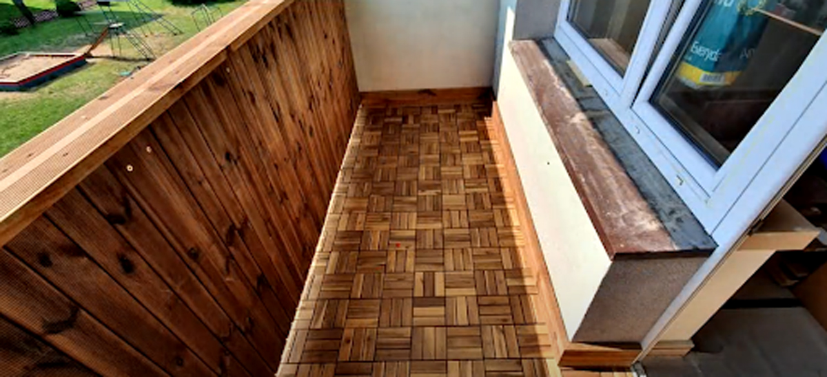 Zrekonstruovaný balkon s dřevěným obložením a moderní dlažbou.