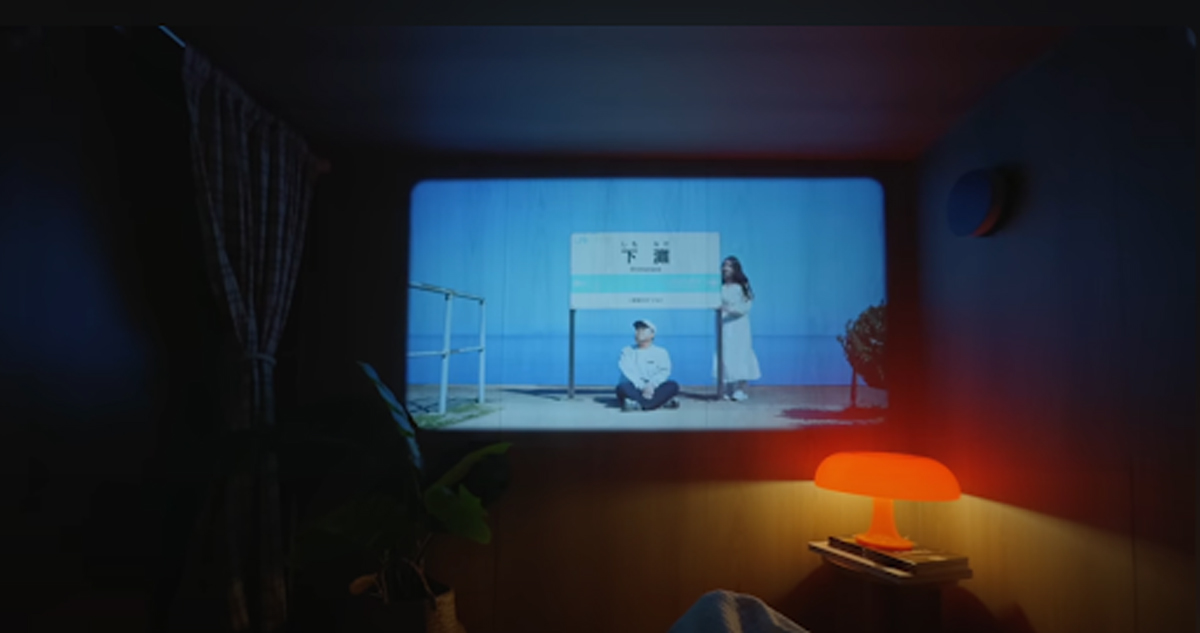 Domácí kino v útulném loftovém bytě – promítání filmu na stěnu s ambientním osvětlením.