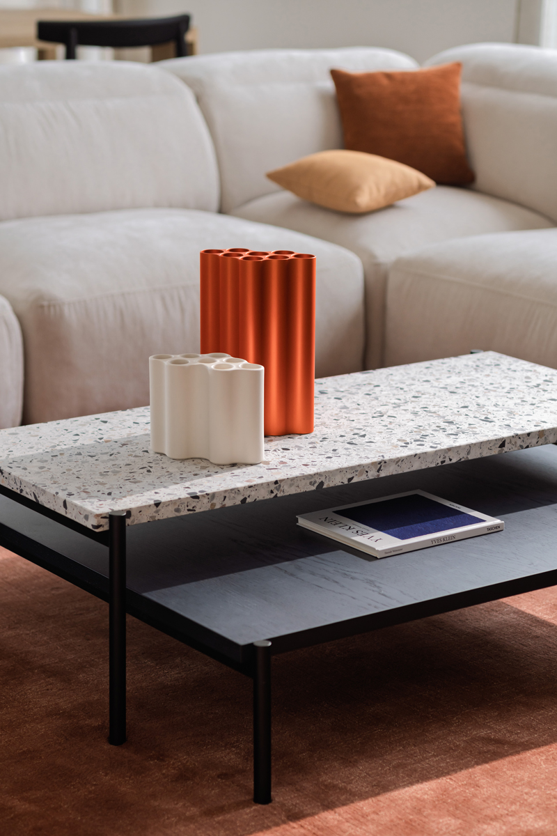 Terrazzo konferenční stolek s designovými vázami v moderním obývacím pokoji.