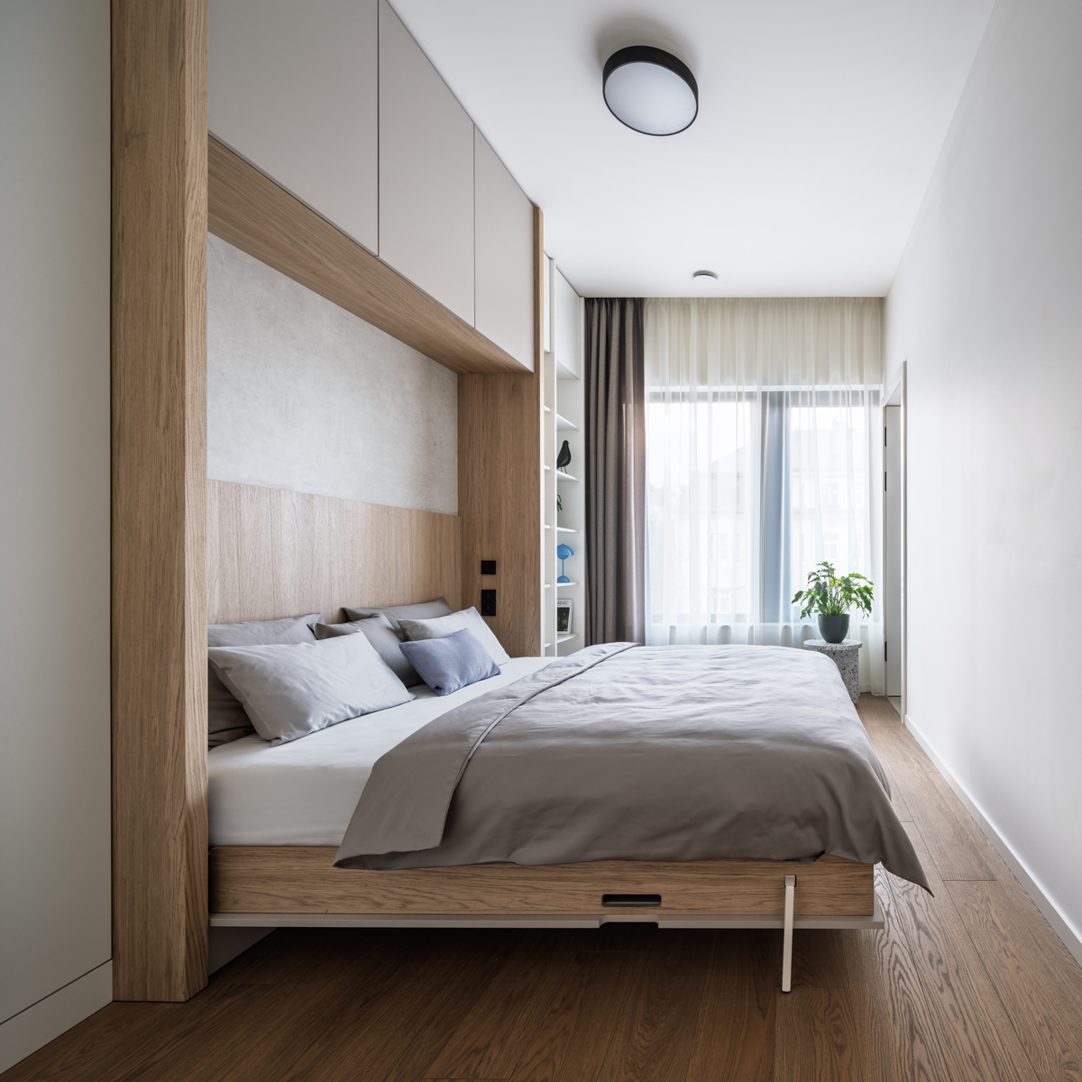 Moderní ložnice s vestavěným úložným prostorem a neutrální barevností.