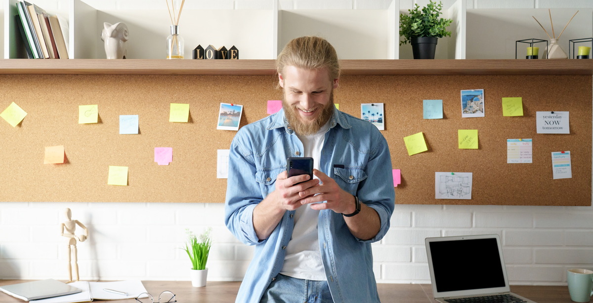 Aplikace pro organizaci domácnosti a plánování úkolů – mladý muž s mobilním telefonem využívá digitální nástroje pro efektivní správu času a povinností.