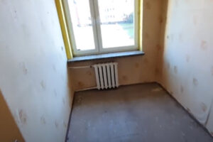 Malý pokoj před rekonstrukcí s původní podlahou a opotřebovanými radiátory.
