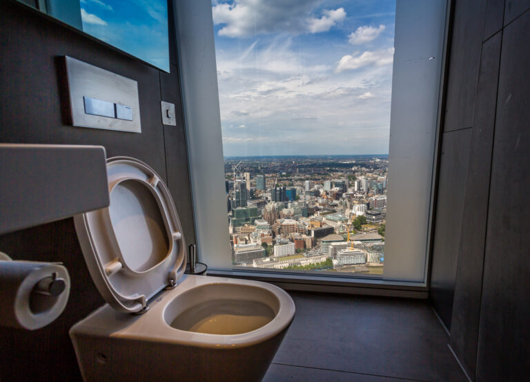 Moderní toaleta s panoramatickým výhledem na mrakodrapy a městskou krajinu.