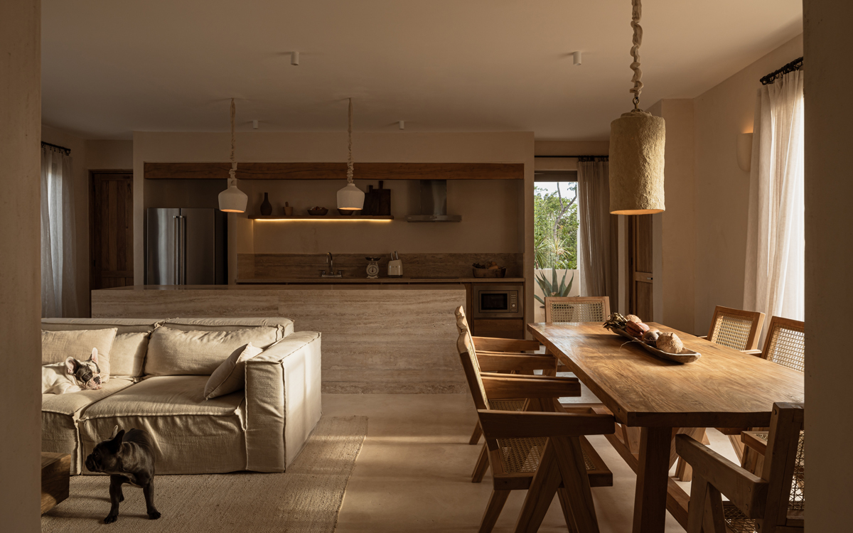 Světlý interiér s otevřenou kuchyní a jídelnou v přírodních tónech, kombinující dřevo, len a minimalistický design.