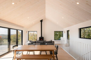 Otevřená denní zóna s jídelním stolem, sedací soupravou a krbovými kamny v čele místnosti.