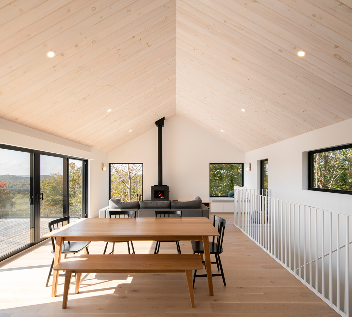 Otevřená denní zóna s jídelním stolem, sedací soupravou a krbovými kamny v čele místnosti.