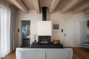 Obývací pokoj s moderním krbem, pohovkou a pohledem do pracovny v rodinném domě v Křenovicích.