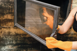 Ruka čistí a leští sklo krbu hadříkem po použití octového roztoku.