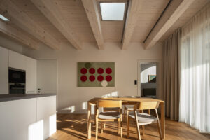 Jídelna s dřevěným stolem, židlemi a originálním obrazem v denní zóně rodinného domu v Křenovicích.