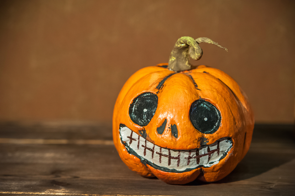 Malovaná dýně s výrazem obličeje, ručně ozdobená černou a bílou barvou.