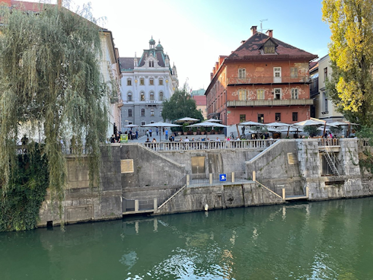 Kavárny a restaurace u řeky Ljubljanice s výhledem na historické domy.