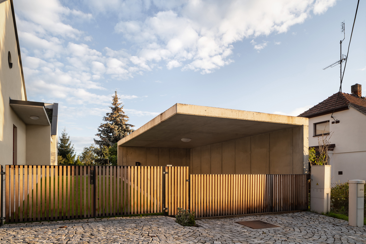 Vstupní branka a dřevěné oplocení s betonovým přístřeškem u rodinného domu v Křenovicích.