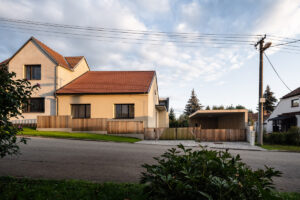 Rodinný dům v Křenovicích s červenou střechou a novým oplocením ve večerním světle.