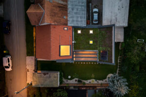 Noční letecký pohled na dům v Křenovicích se zelenou střechou a prosvětlenou přístavbou.