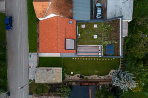 Letecký pohled na rekonstruovaný dům v Křenovicích s červenou a zelenou střechou a pečlivě upravenou zahradou.