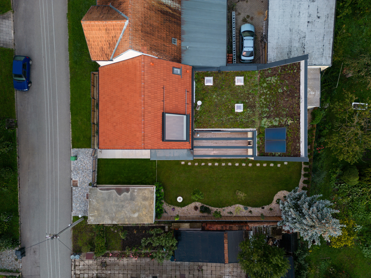 Letecký pohled na rekonstruovaný dům v Křenovicích s červenou a zelenou střechou a pečlivě upravenou zahradou.