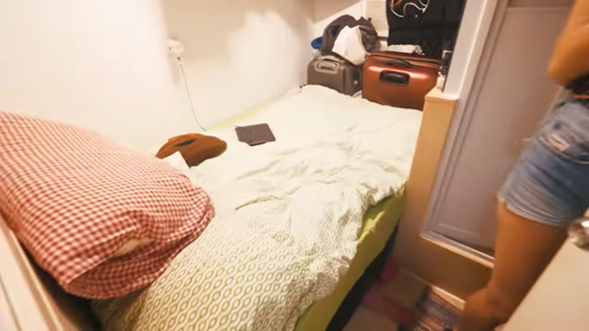 Malý pokoj s postelí a úložným prostorem podél stěn v hongkongském bytě.