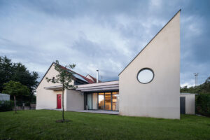 Rekonstruovaný rodinný dům v Křenovicích s moderní přístavbou a výrazným kruhovým oknem.