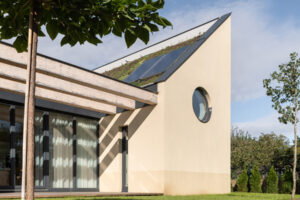 Boční pohled na rodinný dům v Křenovicích se zelenou střechou a solárními panely.