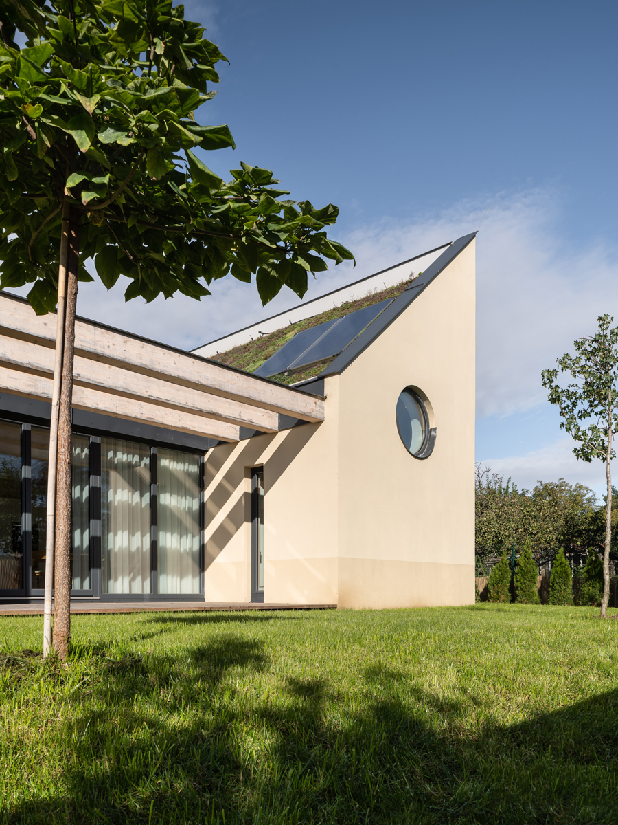 Boční pohled na rodinný dům v Křenovicích se zelenou střechou a solárními panely.