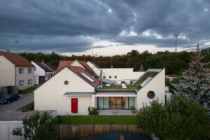 Rodinný dům v Křenovicích s červenou střechou a novým oplocením ve večerním světle.