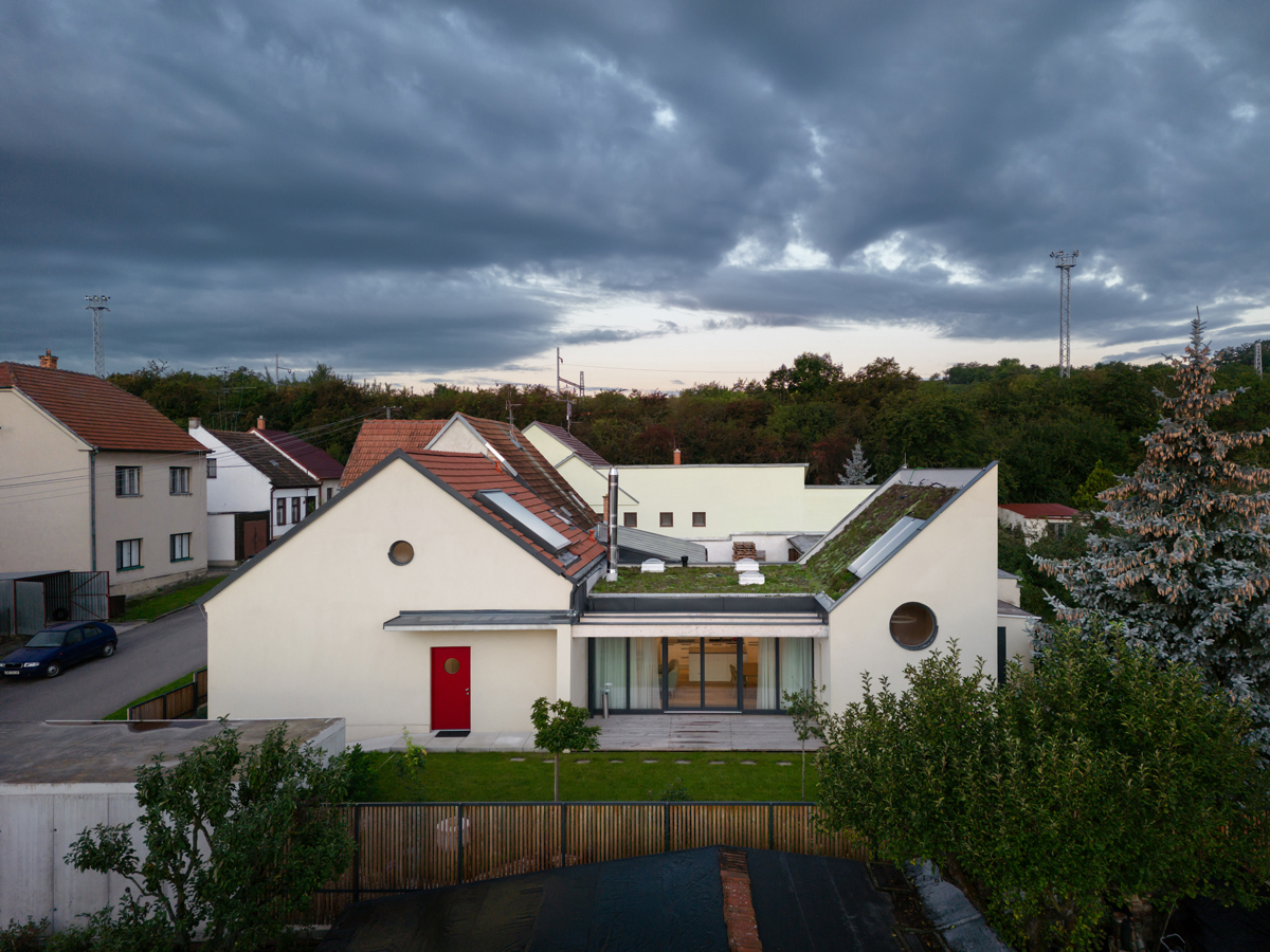 Rodinný dům v Křenovicích s červenou střechou a novým oplocením ve večerním světle.